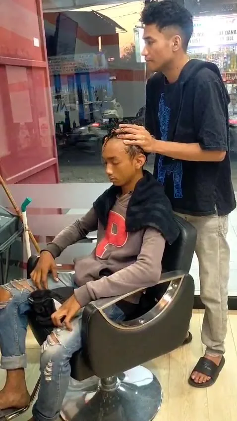 Barber menata rambut pelanggan di kursi barbershop